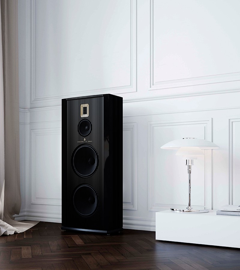 A Model A Steinway Lyngdorf speaker sitting against a wall next to a lamp