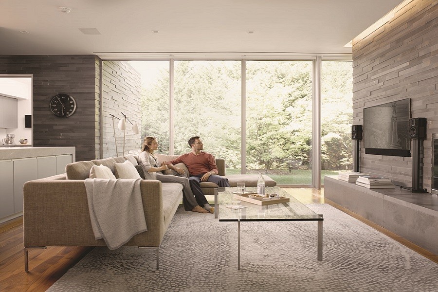 Couple sits in a sunlit room on a stylish couch while listening to music.