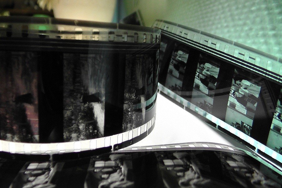 Classic 70mm projection film laid out on the white table with images illuminated from behind.