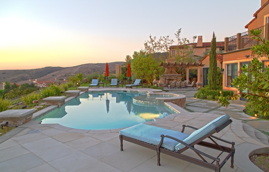 Luxury home with an elegant pool overlooking the manicured property and rolling hills in the background.