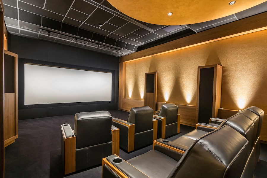  A home theater with a large screen and black leather chairs. 