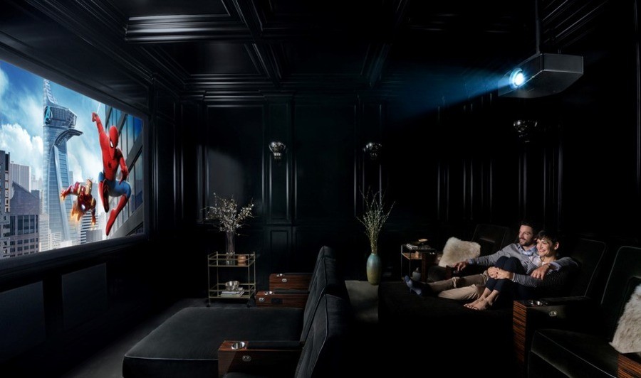 Two people watching a Spiderman movie on a large movie screen in a home theater.