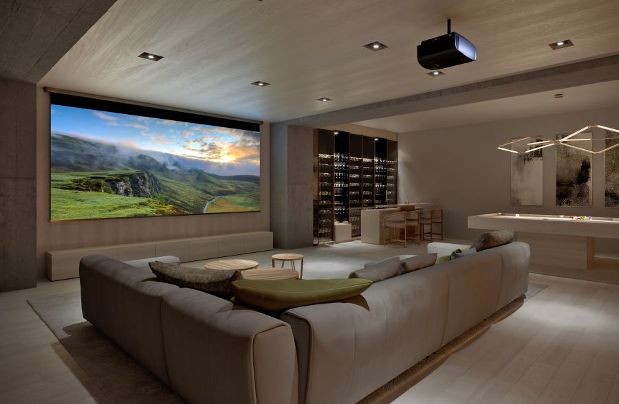A media room with a large screen, projector, sectional, and pool table.