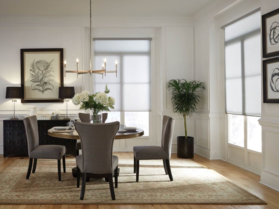 A dining area with a table and chairs. Lowered Lutron window shades let in diffuse sunlight. 