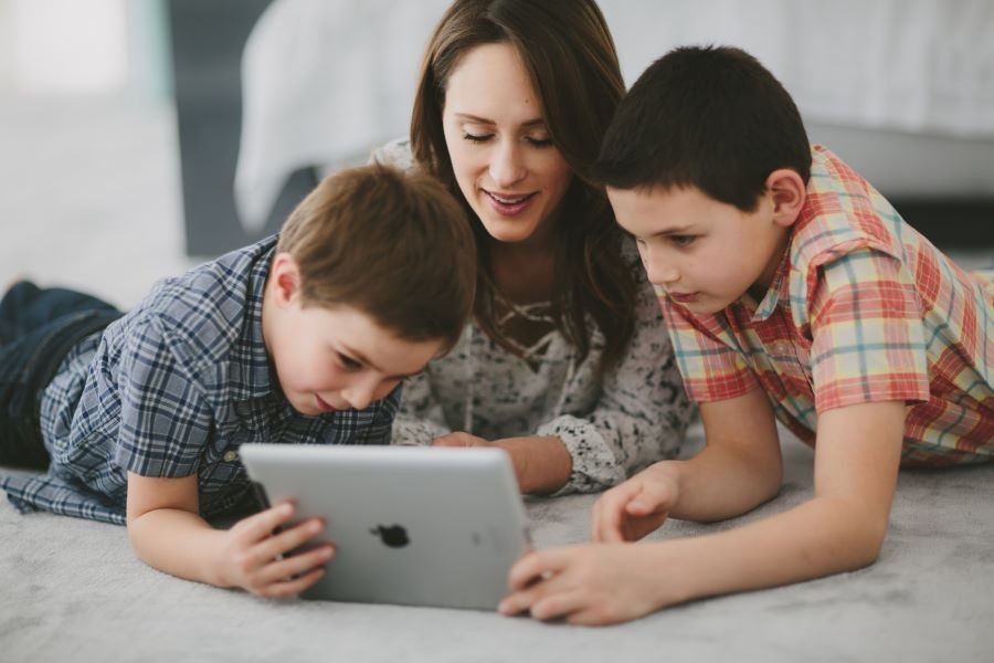 A woman and two children are looking at an iPad that works over home Wi-Fi. 
