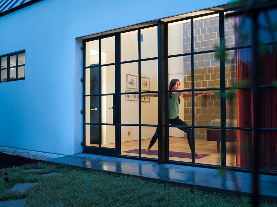A woman practices yoga in a warmly lit room managed by lighting control in Vail. 