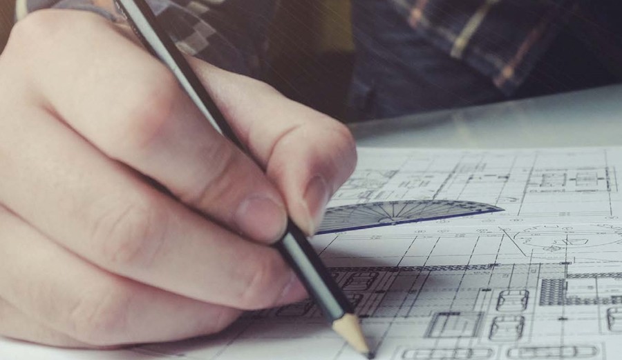The hand of a home theater designer working on a blueprint for a Denver home cinema.