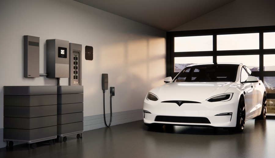 An electric vehicle in a garage with a modern whole-home power system along the wall. 
